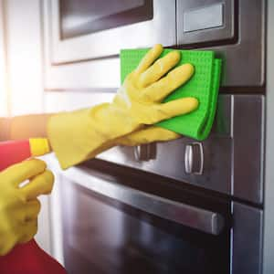 Hands cleaning stainless steel kitchen appliances  